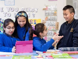 Primary school students collaborating around a tablet in a classroom